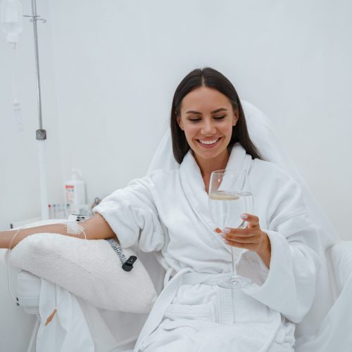 Beautiful woman in white bathrobe drink water